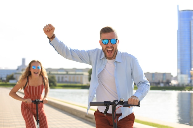 Bella coppia che si diverte a guidare uno scooter elettrico lungo il lungomare della città.