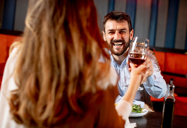 Bella coppia di innamorati sta trascorrendo del tempo insieme e brindare ai bicchieri nel moderno ristorante