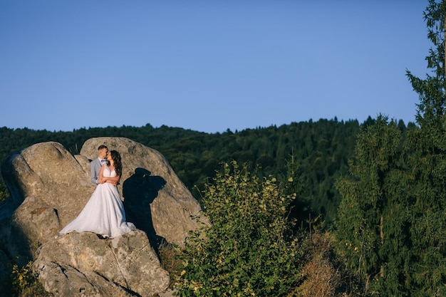 Bella coppia di sposi novelli sposi in abiti da sposa che camminano sullo sfondo delle montagne