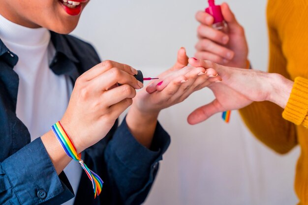 Bella coppia gay che si trucca dipingendosi le unghie e sorridendo essendo romantico al chiuso a casa concetto lgbt