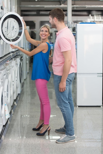 Bella coppia giovane Shopping per lavatrice nel reparto prodotti di un supermercato supermercato poco profondo del campo