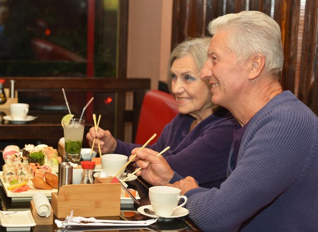 Bella coppia matura che mangia sushi al bar