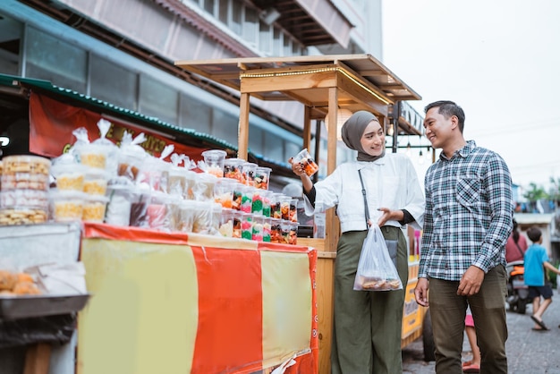 Bella coppia musulmana sta facendo acquisti in una bancarella di cibo o in un venditore ambulante durante il ramadan