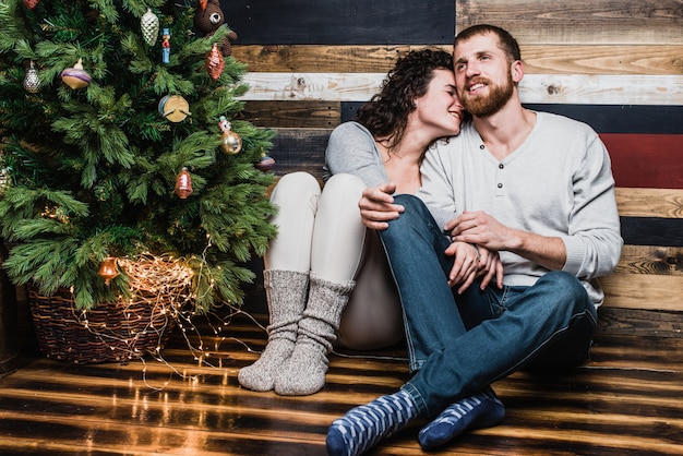 Bella coppia seduta vicino all&#39;albero di Natale. Concetto di Natale e Capodanno