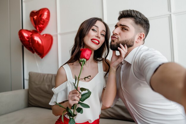 bella coppia uomo e donna con palloncini a forma di cuore e rosa rossa