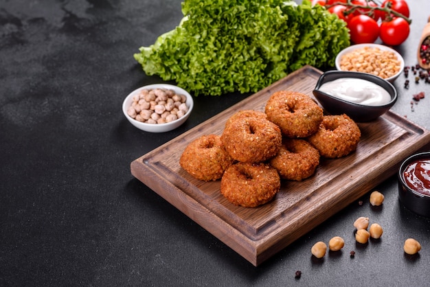 Bella deliziosa fresca falafel di ceci con salse su uno sfondo concreto. Elementi di cucina vegetariana