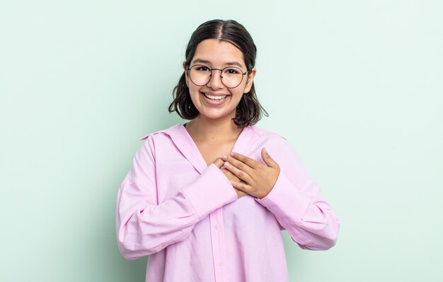 Bella donna adolescente che si sente romantica, felice e innamorata, sorride allegramente e si tiene per mano vicino al cuore