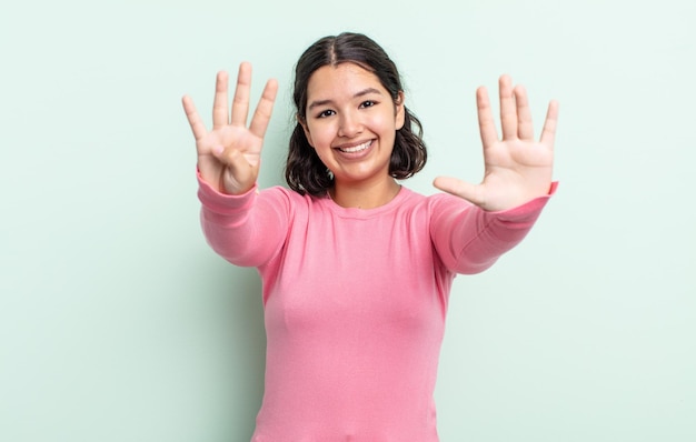 Bella donna adolescente che sorride e sembra amichevole, mostrando il numero nove o nono con la mano in avanti, conto alla rovescia