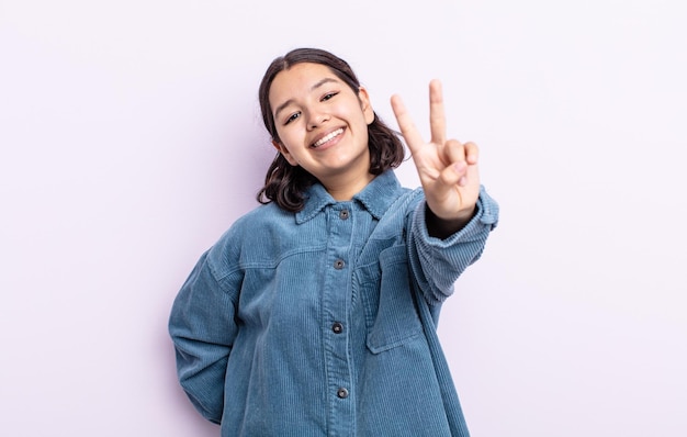 Bella donna adolescente che sorride e sembra felice, spensierata e positiva, gesticolando vittoria o pace con una mano