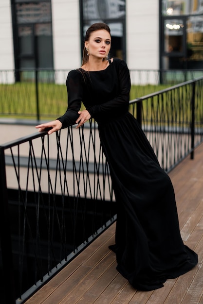 Bella donna adorabile con trucco di moda in vestito nero di lusso che lavora come posa del modello