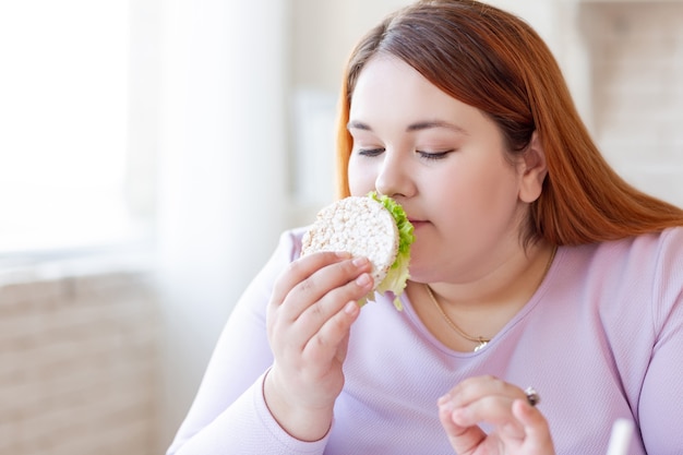 Bella donna affamata che tiene un panino mentre lo annusa