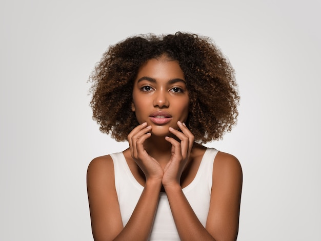 Bella donna africana bianca t-shirt ritratto taglio di capelli afro che tocca il suo viso Colore di sfondo grigio