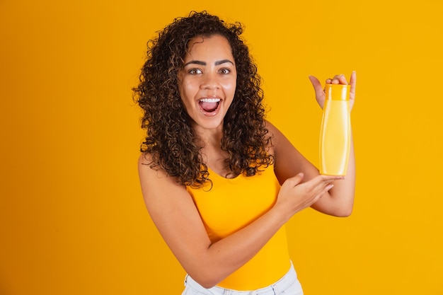 Bella donna afro che tiene in mano un pacchetto di prodotti per capelli.