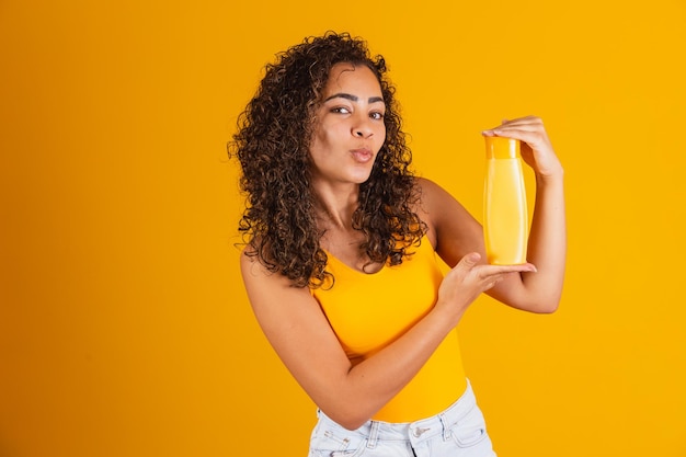 Bella donna afro che tiene in mano un pacchetto di prodotti per capelli.