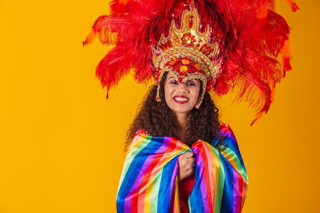 Bella donna afro in abito di carnevale bandiera lgbt su sfondo giallo.