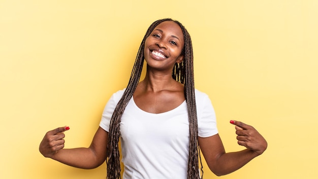 Bella donna afro nera che sembra orgogliosa, arrogante, felice, sorpresa e soddisfatta, che indica se stessa, sentendosi una vincitrice