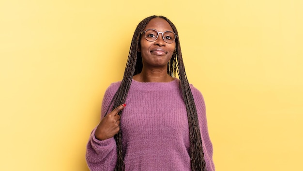 Bella donna afro nera che sembra orgogliosa, fiduciosa e felice, sorridente e che indica se stessa o fa il segno numero uno