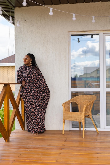 Bella donna afroamericana che si gode la serata sul villaggio e la natura sulla terrazza della casa di campagna Concetto di diversità e inclusione e cottagecore