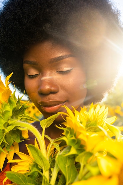 Bella donna afroamericana con capelli ricci stile afro in un campo di girasoli