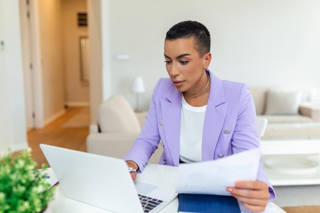 Bella donna afroamericana freelance che annota le informazioni per il progetto di pianificazione che fa un lavoro a distanza tramite computer portatile donna che ride mentre legge la posta elettronica sul moderno dispositivo portatile