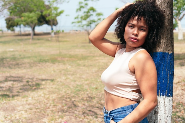 Bella donna afroamericana in posa in un parco soleggiato