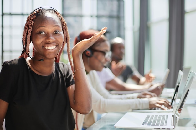 Bella donna afroamericana sorridente che lavora nella call center con la squadra varia