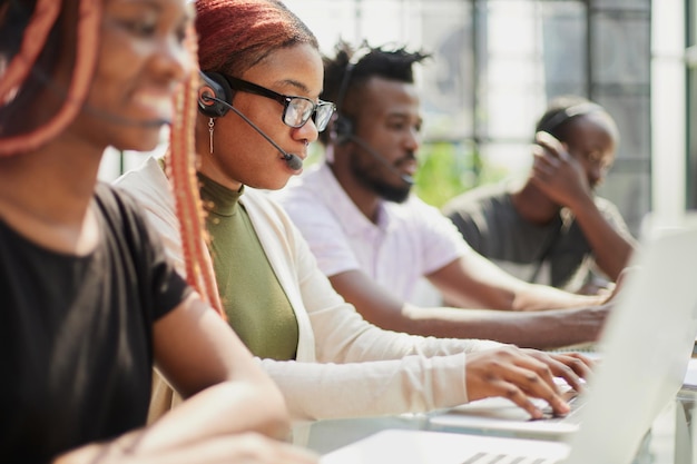 Bella donna afroamericana sorridente che lavora nella call center con la squadra varia