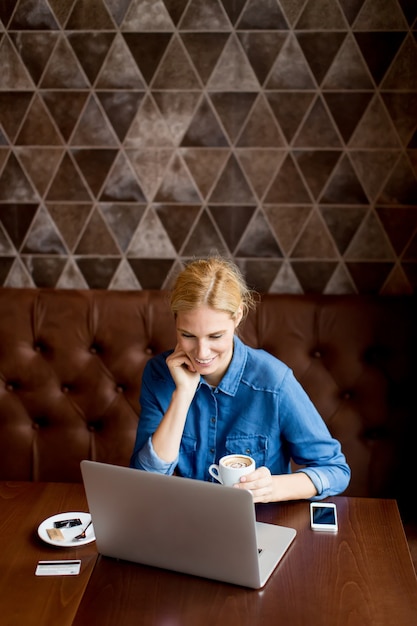 Bella donna al caffè con laptop avendo una pausa caffè