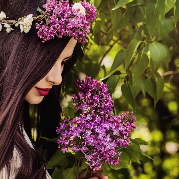 Bella donna all'aperto su foglie verdi e fiori lilla sullo sfondo