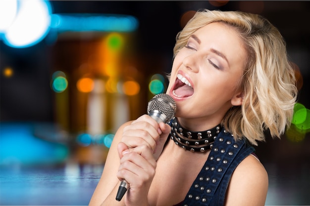 Bella donna alla moda che canta al karaoke isolato su sfondo