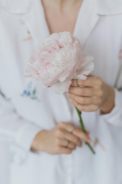 Bella donna alla moda che tiene peonia rosa Giovane donna in camicia floreale boho con fiore in mano