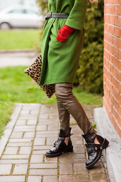 Bella donna alla moda nel parco d'autunno con impugnatura leopardo e cappotto verde.