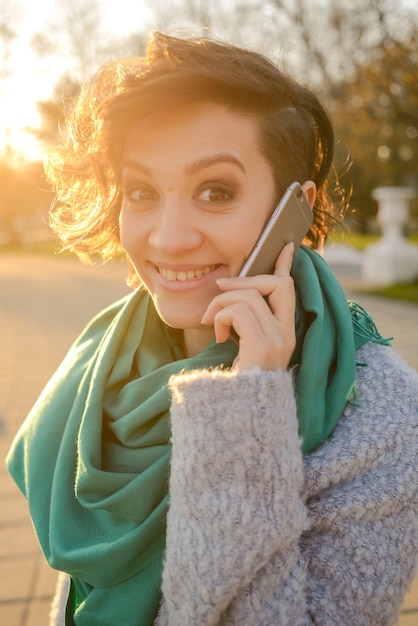 Bella donna allegra con il telefono cellulare nel parco