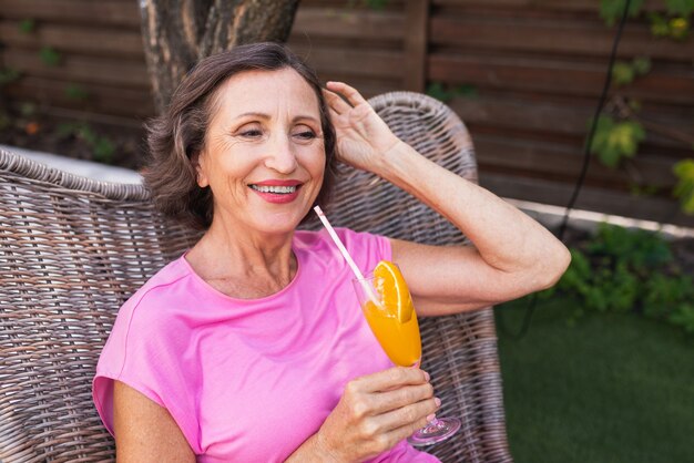 Bella donna anziana che si rilassa a casa in giardino - Una signora abbastanza matura riposa in un tranquillo giardino sul retro