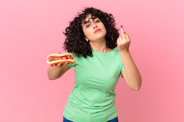 bella donna araba che si sente arrabbiata, infastidita, ribelle e aggressiva e tiene in mano un hot dog