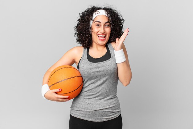 Bella donna araba che si sente felice e stupita da qualcosa di incredibile e tiene in mano un concetto di sport con palla da basket