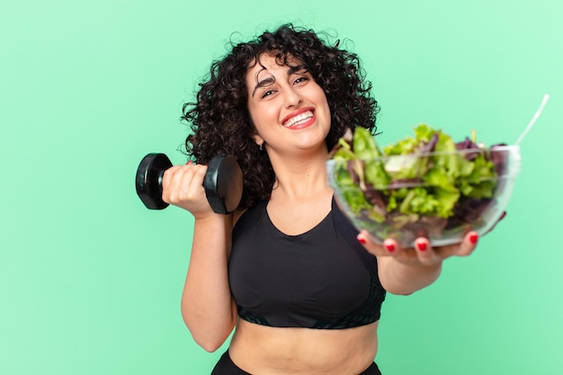 Bella donna araba con un manubrio e un'insalata. concetto di fitness