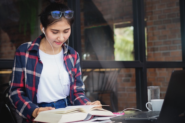 bella donna Asia, ragazza ascoltando musica e leggendo il libro con felice nel tempo libero.