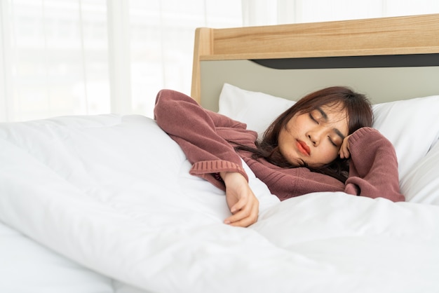 bella donna asiatica che dorme sul letto in mattinata