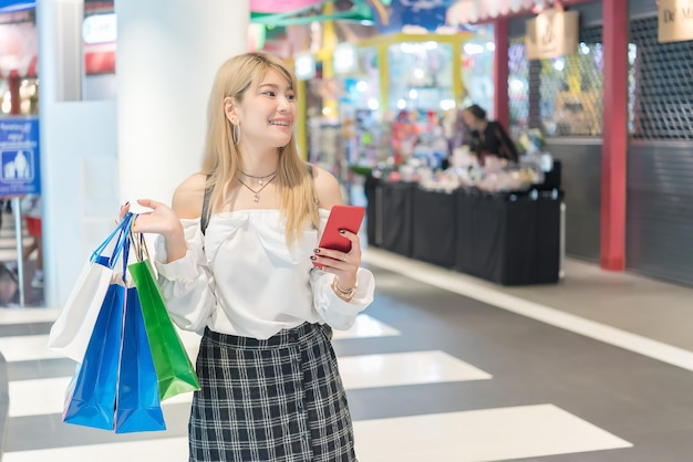 Bella donna asiatica che fa shopping con le borse della spesa al grande magazzino La gente della Thailandia acquista al centro commerciale Stile di vita della ragazza moderna Concetto di donna felice