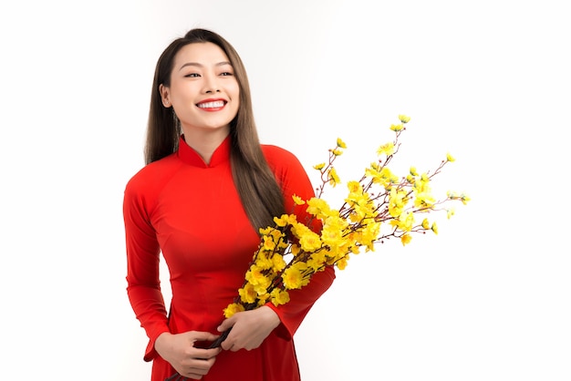 Bella donna asiatica che indossa il tradizionale Ao dai del Vietnam che tiene in mano un fiore di pesco durante le vacanze di Tet.