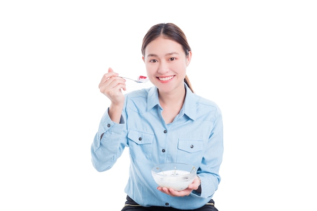 Bella donna asiatica che mangia yogurt con la frutta sopra priorità bassa bianca