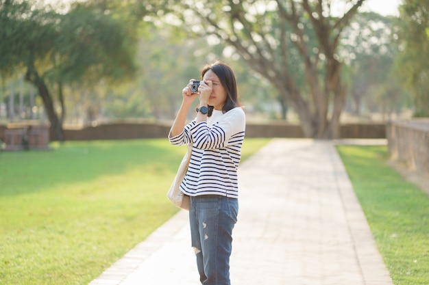 Bella donna asiatica che prende le foto al parco