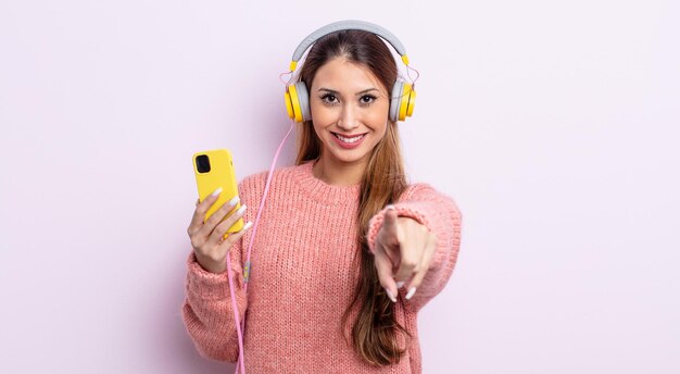 Bella donna asiatica che punta alla telecamera scegliendo te. concetto di cuffie e telefono