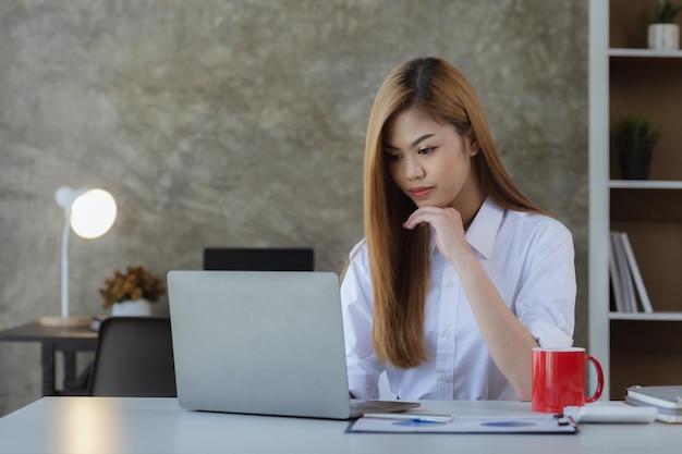 Bella donna asiatica che scrive con il suo laptop è un uomo d'affari giovane ed energico per gestire una società di avvio che conduce affari con la politica della nuova generazione