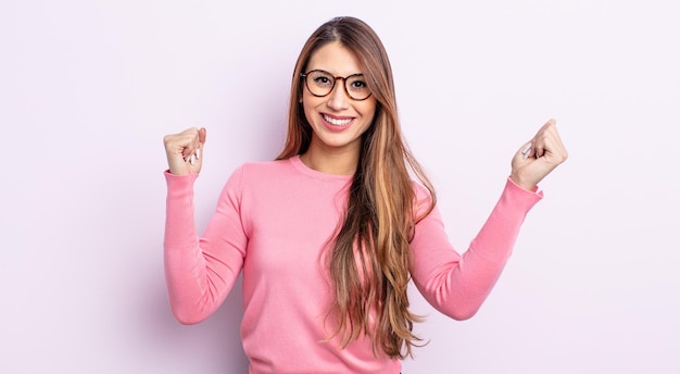 Bella donna asiatica che si sente felice, positiva e di successo, celebrando la vittoria, i risultati o la buona fortuna