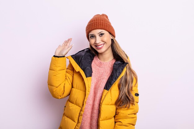 Bella donna asiatica che sorride felicemente, agitando la mano, accogliendoti e salutandoti. concetto di inverno