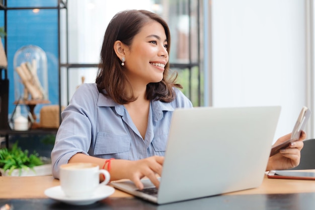 Bella donna asiatica che utilizza computer portatile in caffetteria