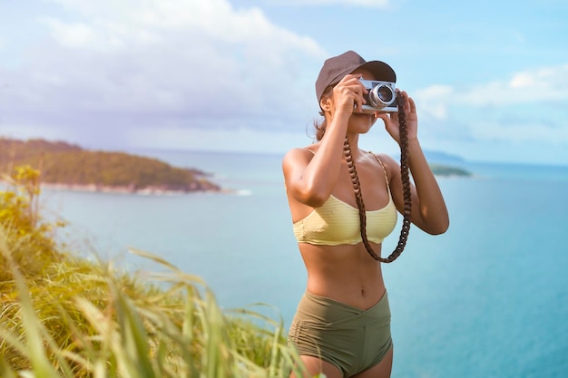 Bella donna asiatica in abiti sportivi che scatta foto sul picco di montagna del mare dopo il trekking