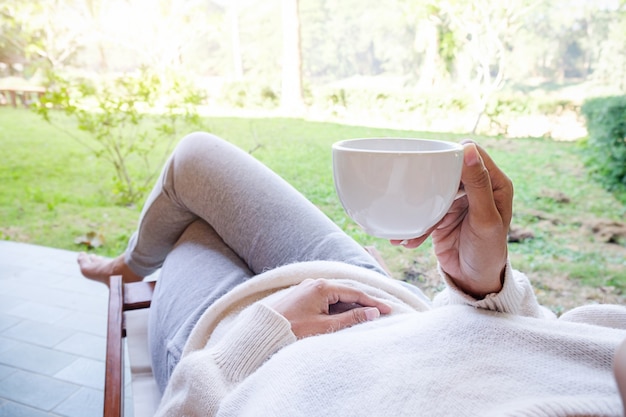 Bella donna asiatica nel giardino con una tazza di caffè